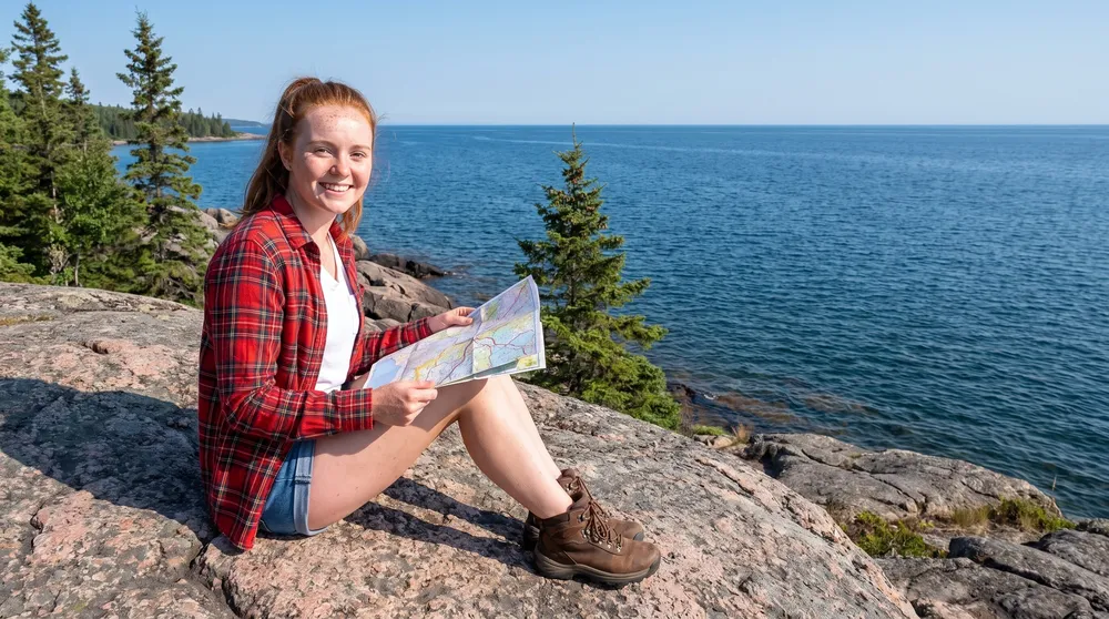A woman on a granite shore with a road map